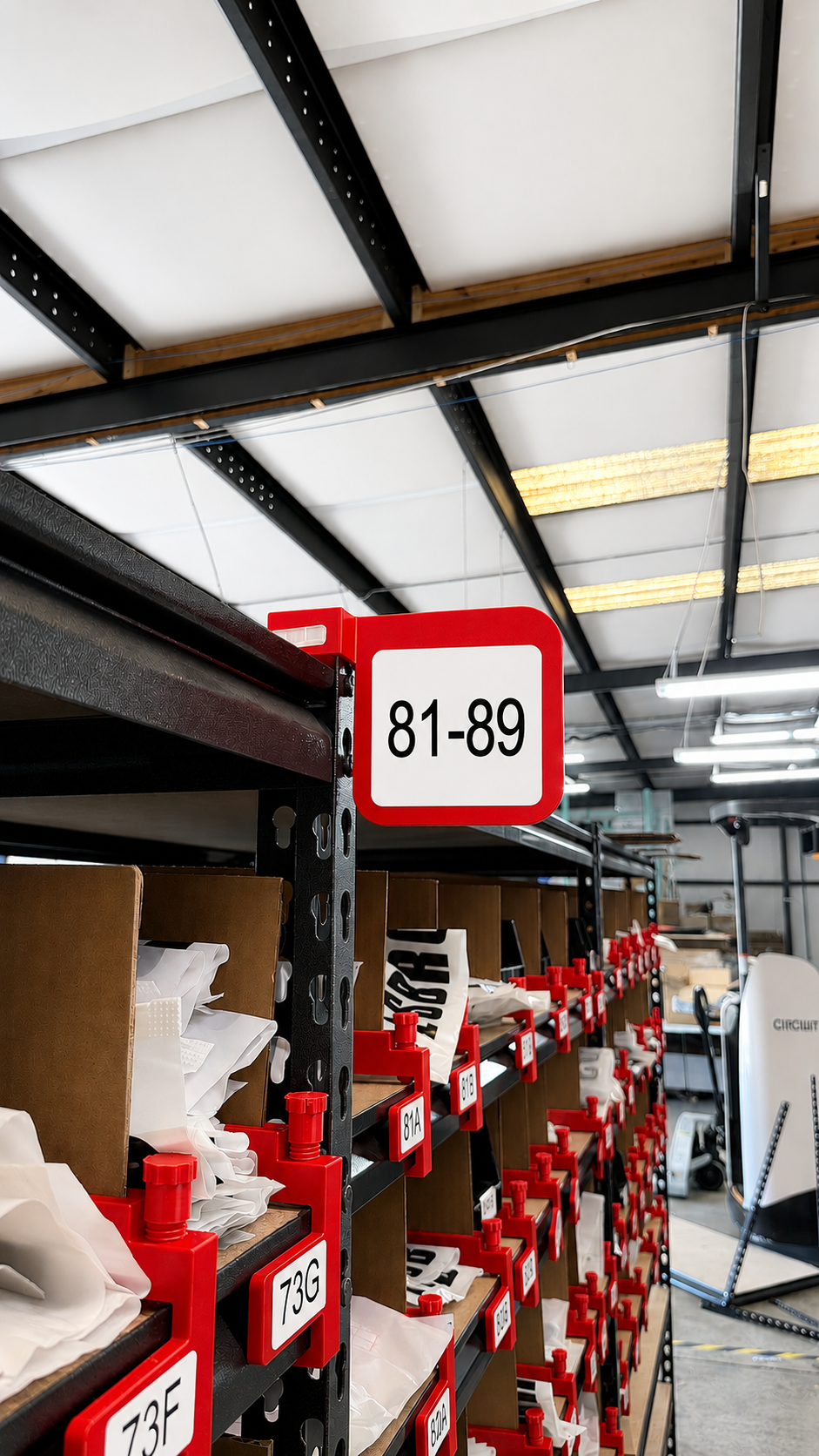 Top-of-shelf brackets installed on warehouse pick rack with 81-89 zone signage